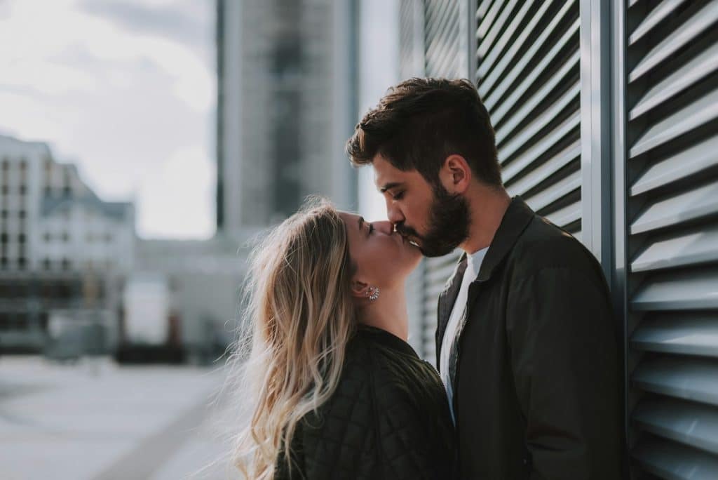 The couple is kissing outdoors.