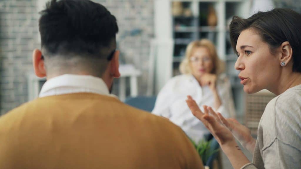 A woman talking to a man at a table.