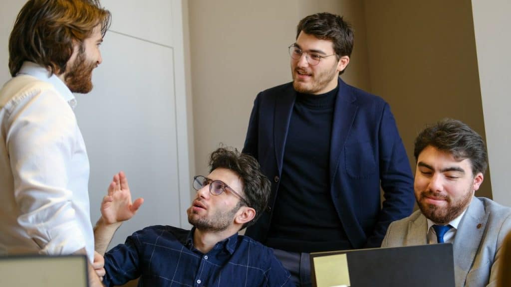 Four men having an engaged discussion in an office setting.