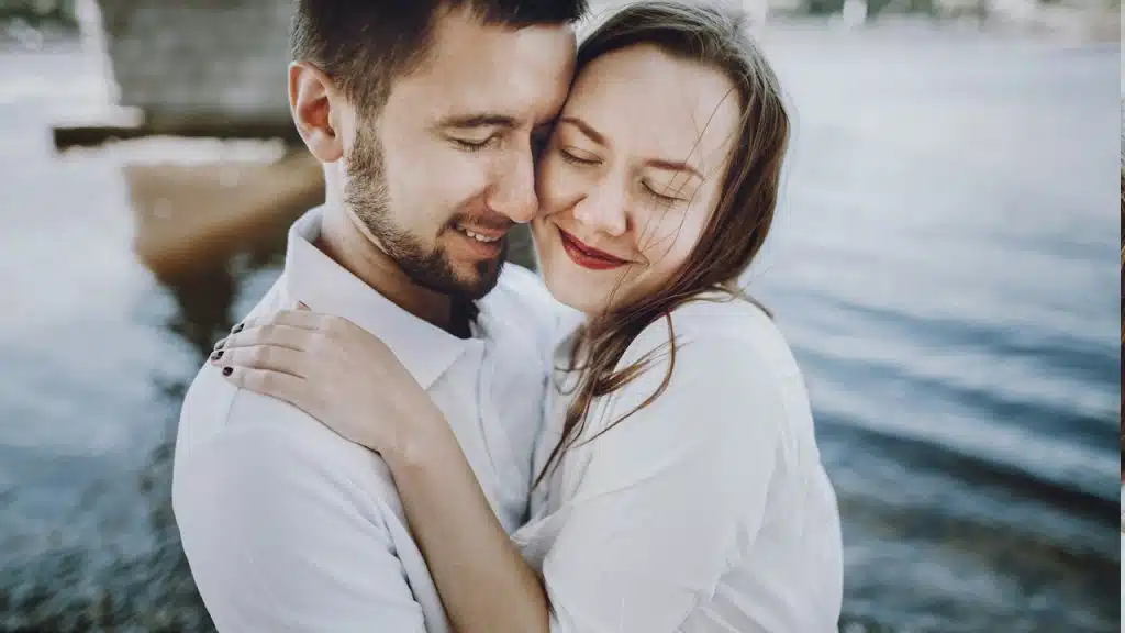 A happy, stylish couple in love hugging on the beach in summer.