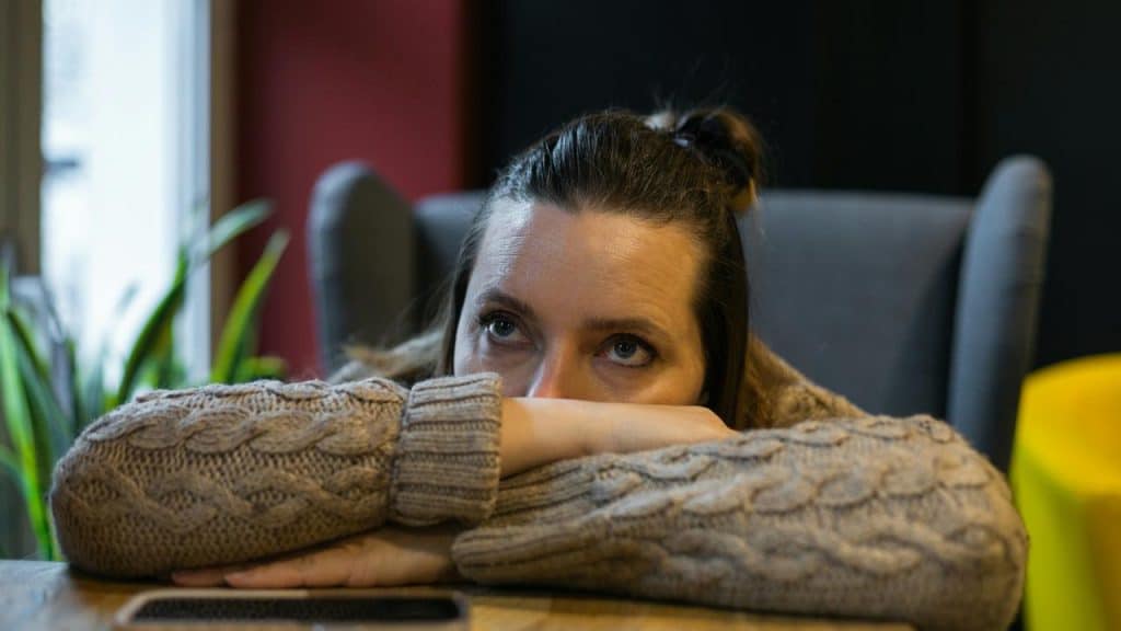 A woman resting her head on her arms while staring ahead.