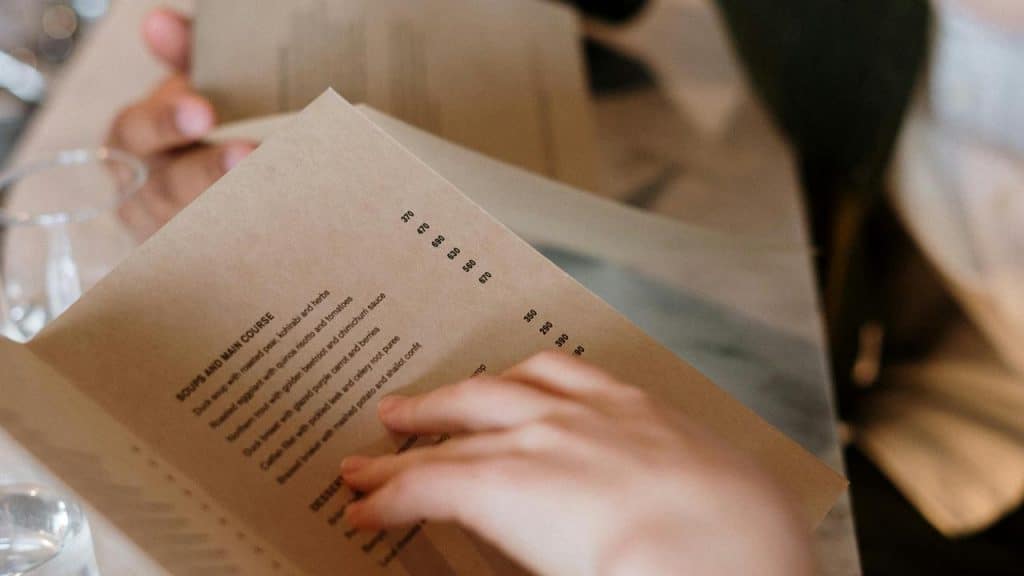 A person reading a restaurant menu at a table.