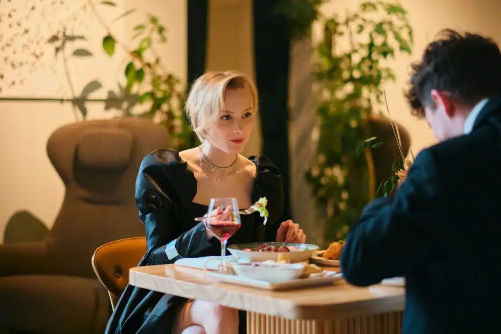 A confident woman sitting across the man at a fancy restaurant.