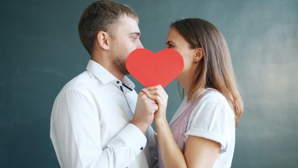 A couple holding a red heart obscuring faces.