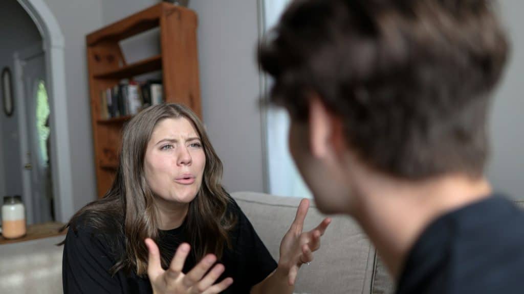 A woman sitting on a couch talking to a man.