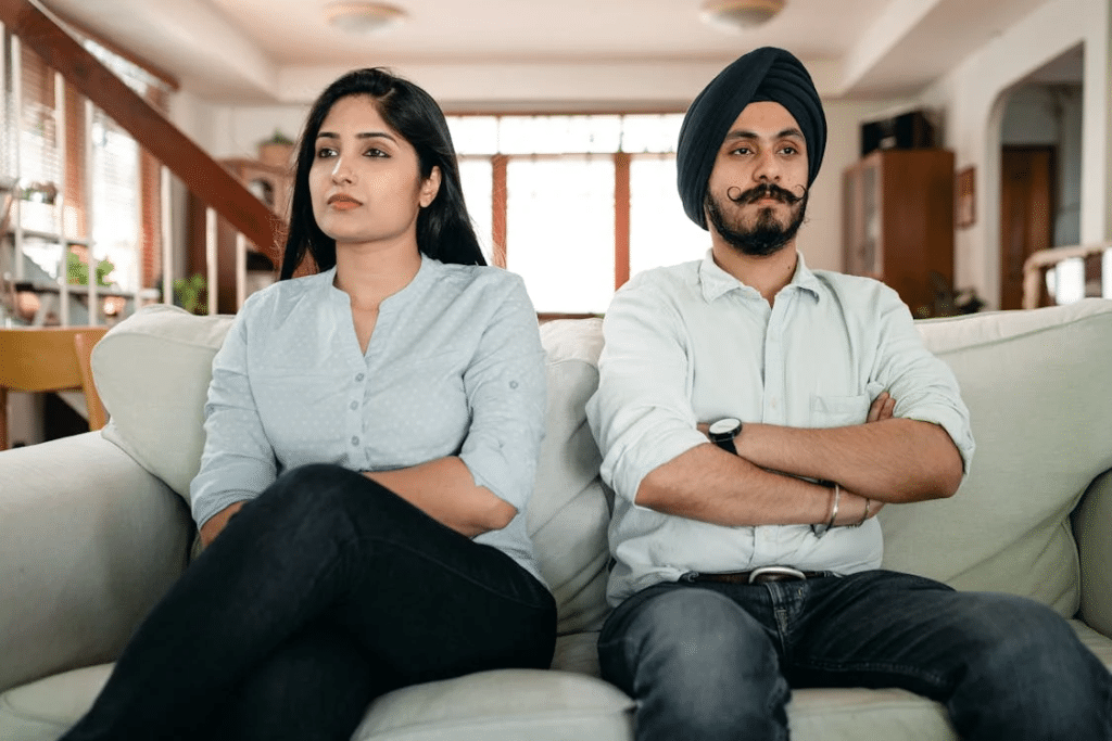 Offended young Indian couple sitting on sofa