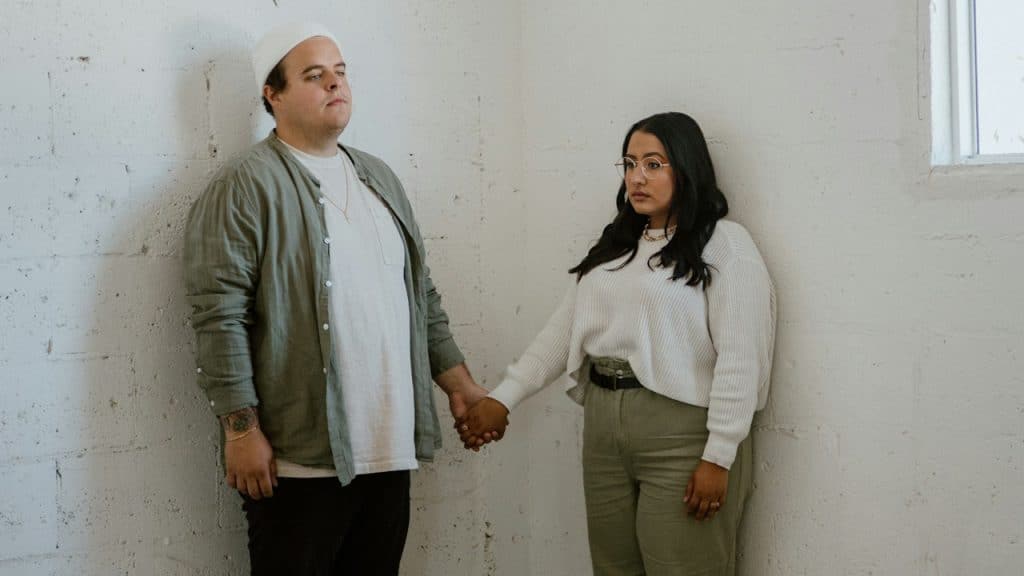 A man and a woman holding hands while standing in an empty room.