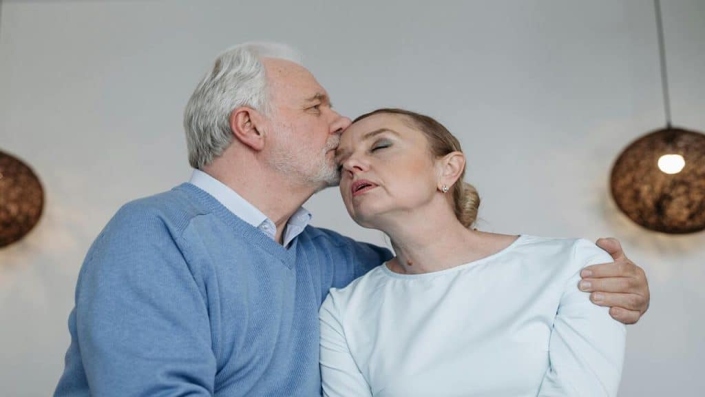 A man kissing his wife’s forehead