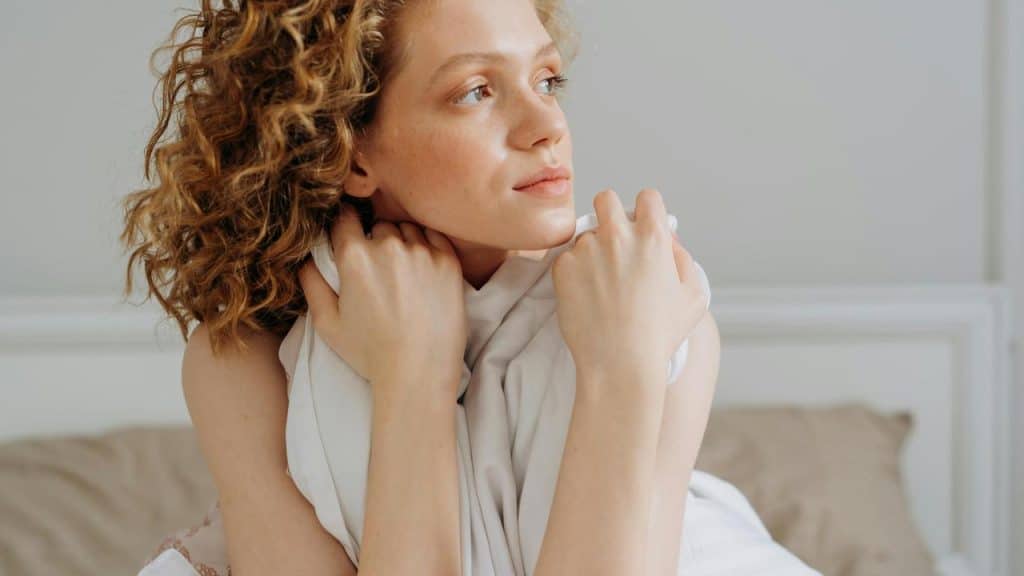 A woman sitting on a bed holding a pillow.