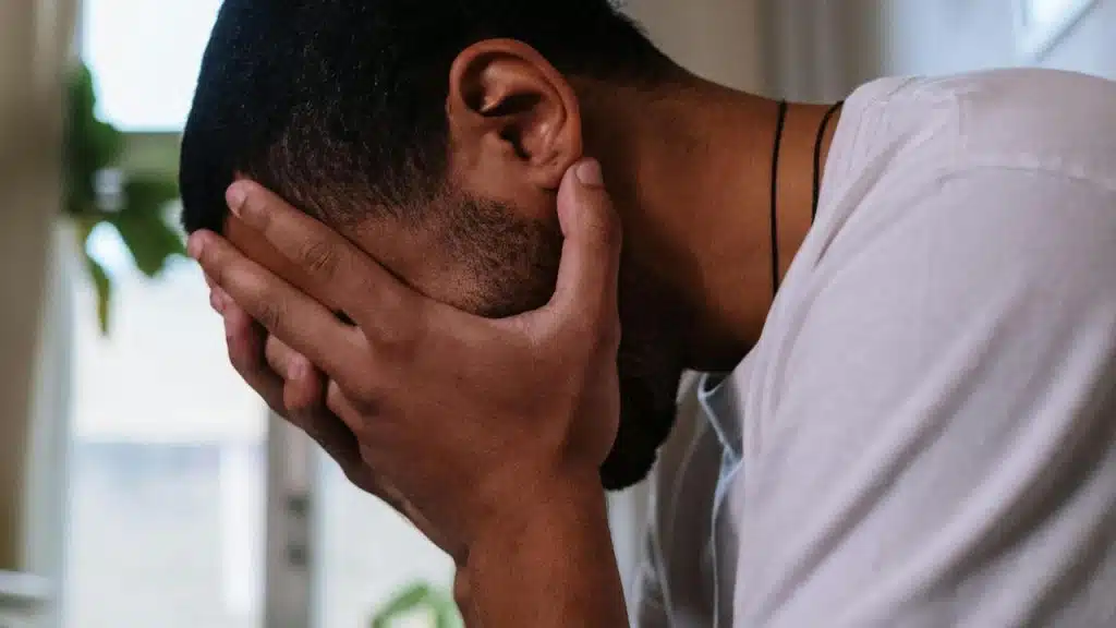 A man sitting with his head in his hands looking distressed.