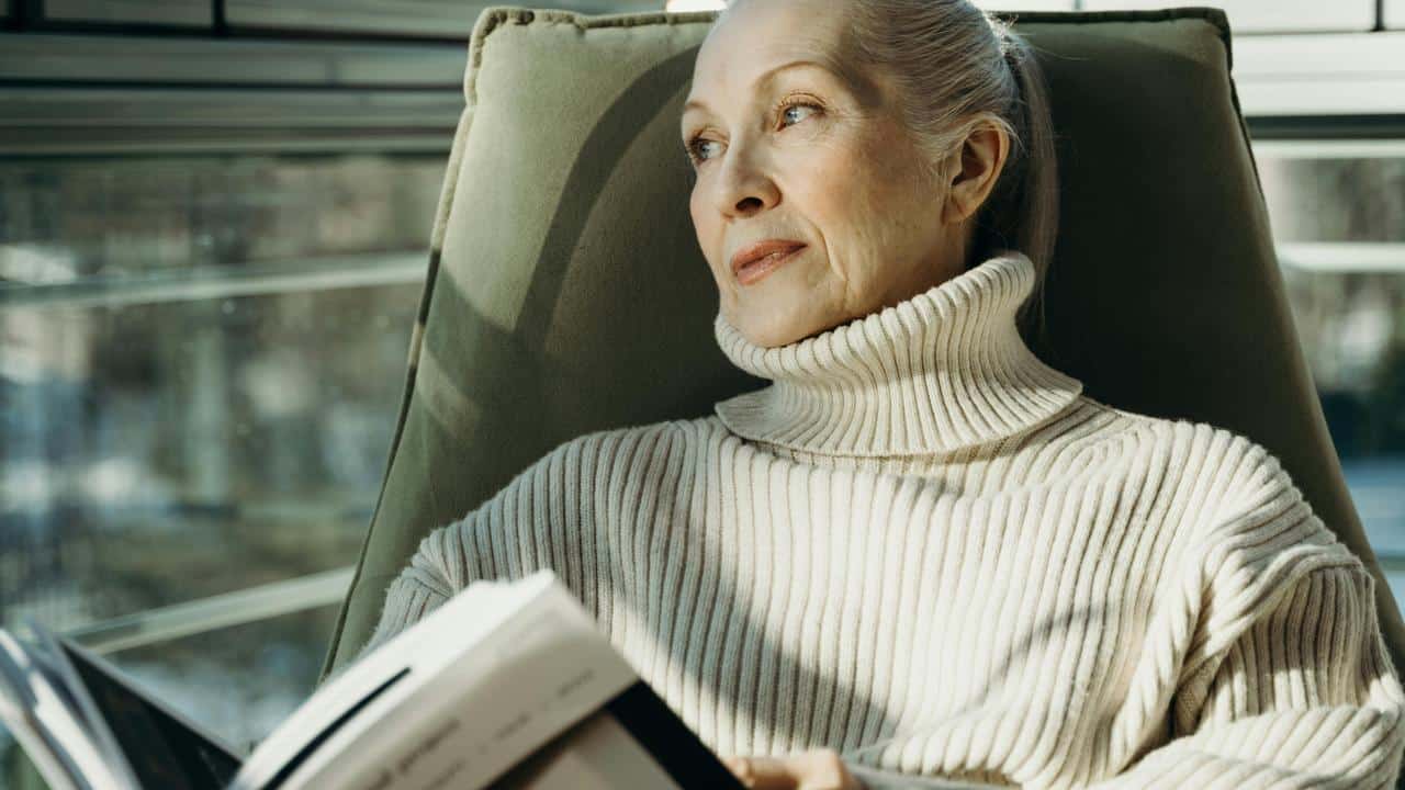 A woman relaxing in a chair while reading a book.