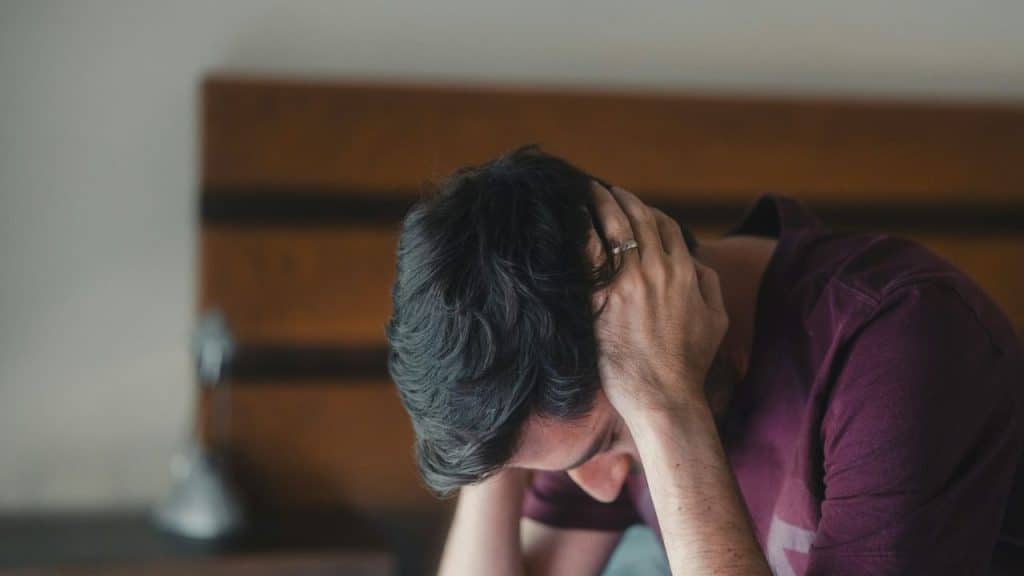 Man wearing a ring covers his head with his hands in distress.