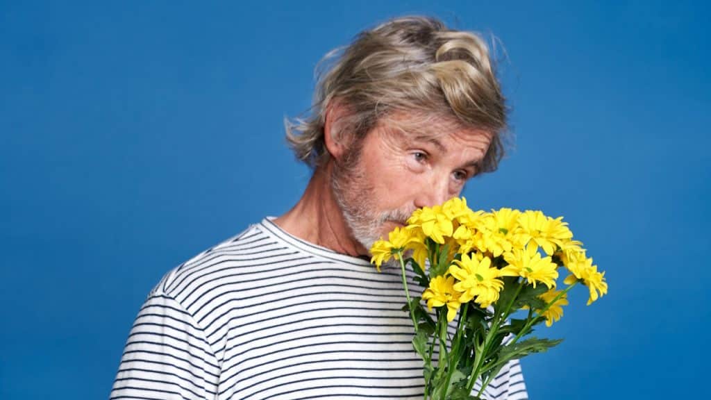 A man holding a bunch of yellow flowers.