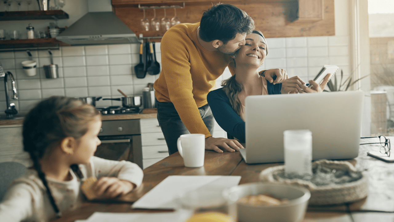 A man kissing his wife during breakfast