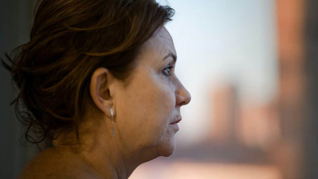 Profile close-up of a middle-aged woman looking out a window.