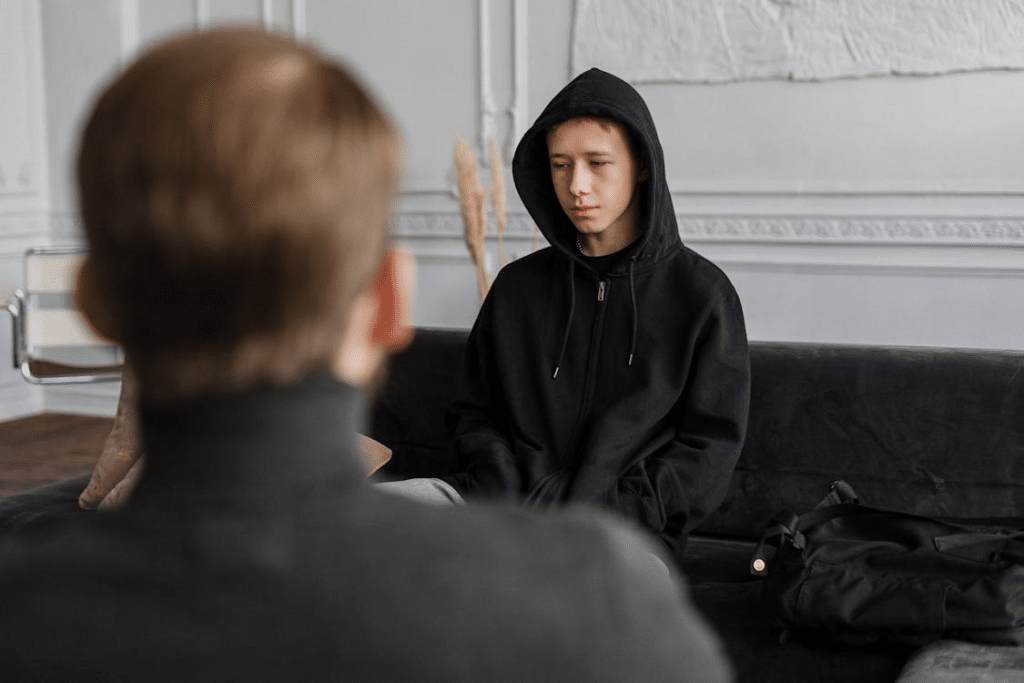 Man in Black Hoodie Sitting Beside Boy in Black Hoodie