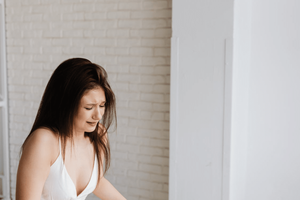 Woman in white tank top crying near the brick wall