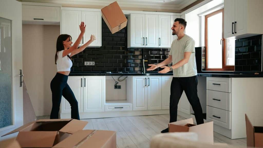 A couple joyfully unpacks boxes together in their new kitchen.