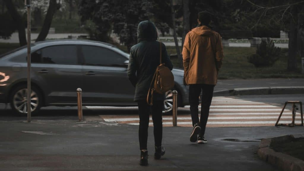 A woman standing while a man walks away from her on a street.