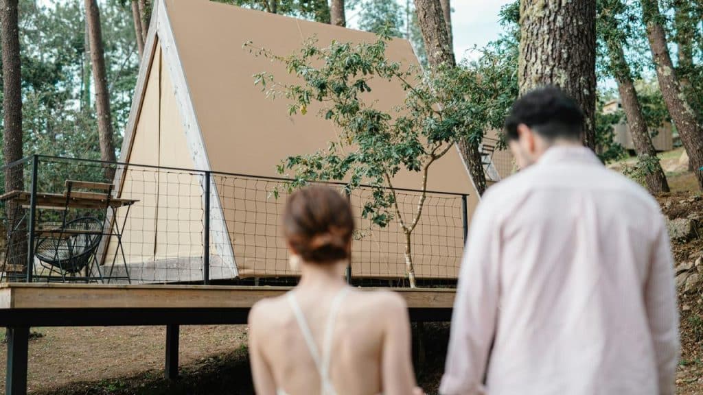 A couple walking together in front of a wooden cabin.