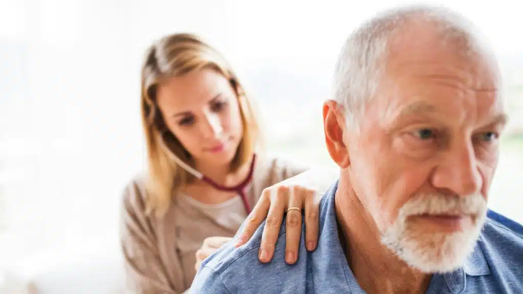A younger woman holding the shoulder of an older man.