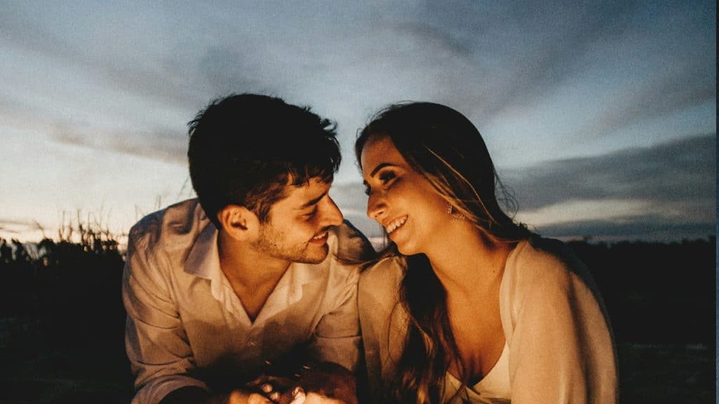 A man looking at a woman at dusk outdoors.