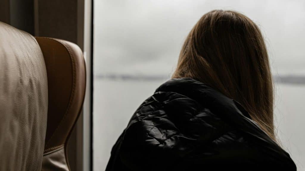 A woman looking out a window on a cloudy day.