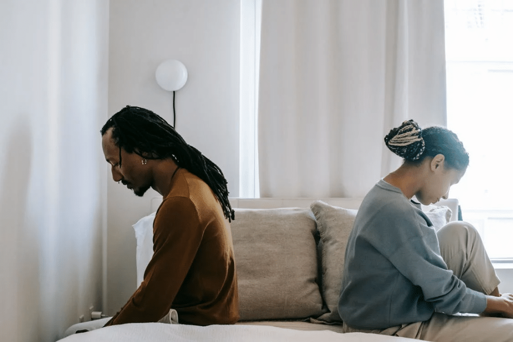 Concerned black couple sitting on bed in misunderstanding