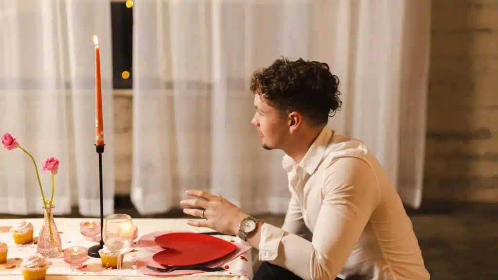 A man sitting at a table with a red paper heart on a plate.