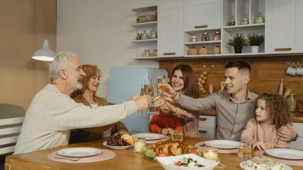 A family sitting around a dinner table raising glasses in a toast.
