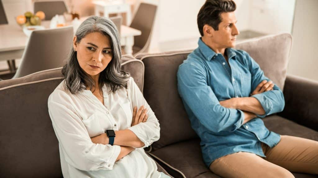 A mature couple sitting on a couch after a quarrel.