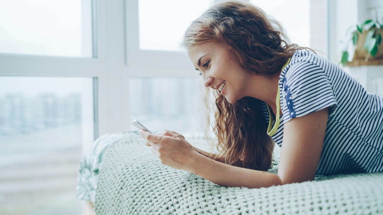 A woman smiling while texting 