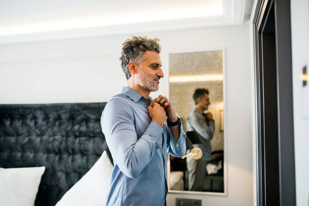 A man dressing up in a hotel room.