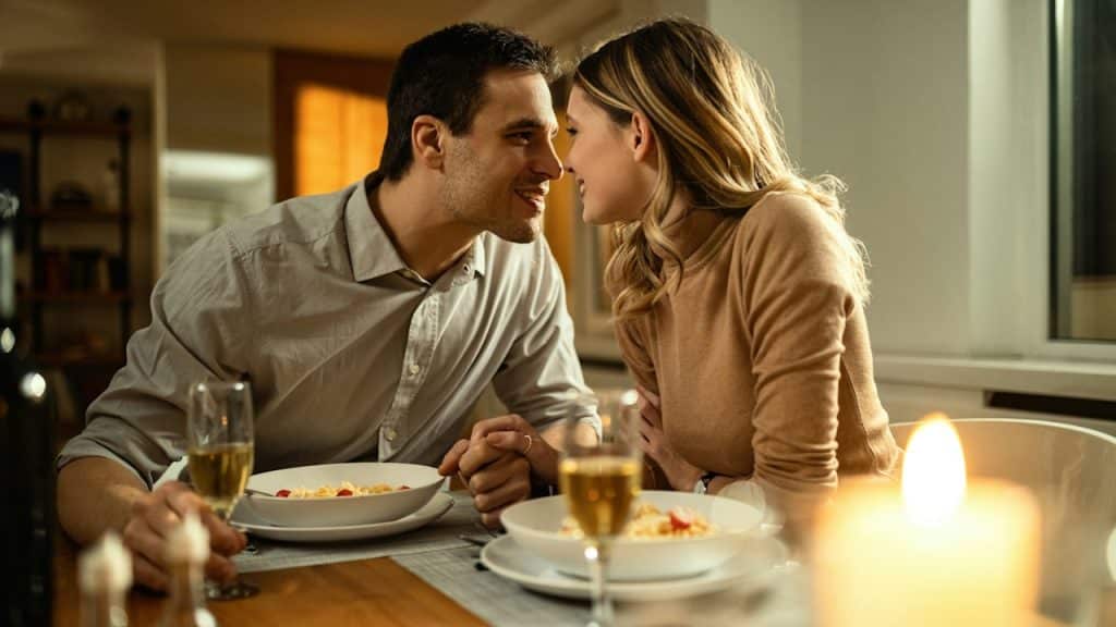 A romantic couple holding hands during dinner at a dinner table.