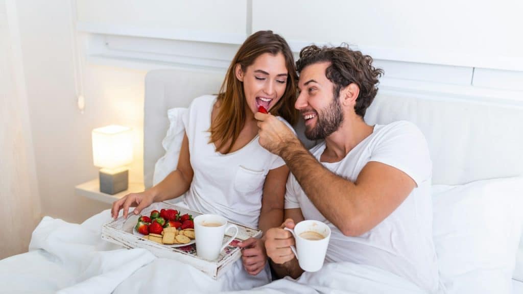 A couple in love having breakfast together in bed.