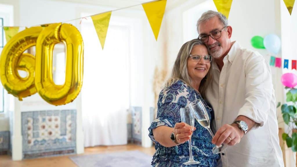 An older couple celebrating a 60th birthday or anniversary with champagne and decorations.