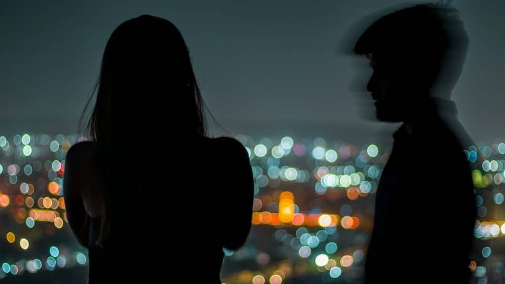 A woman standing in the dark while imagining her Ex with her.