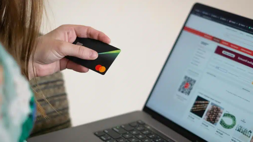A person holding a credit card while shopping online on a laptop.
