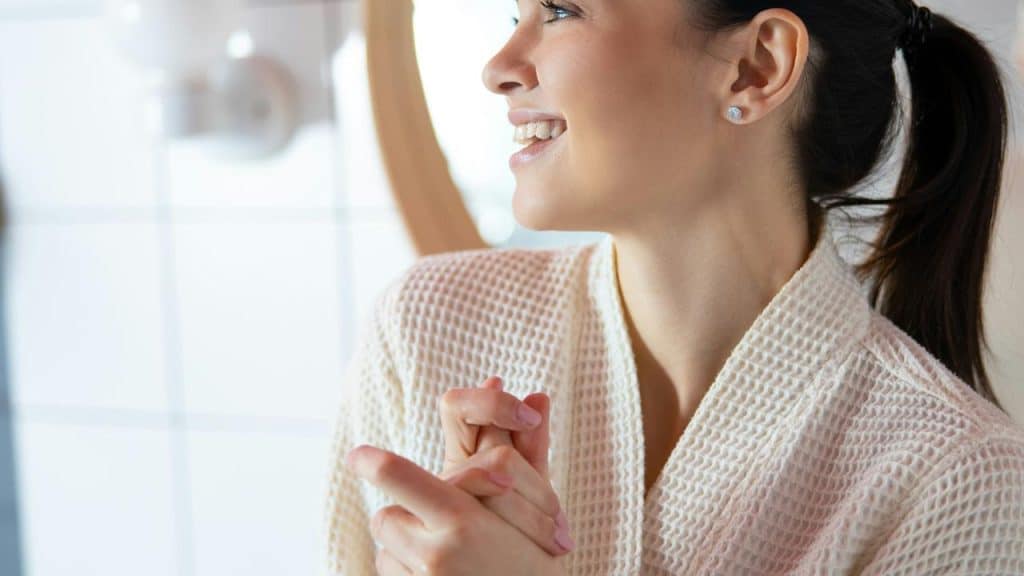 A smiling woman in a bathrobe looking to the side.