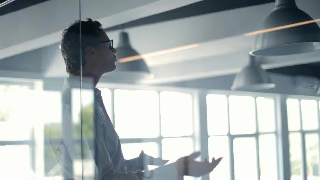 A man speaking while standing in a modern office space.