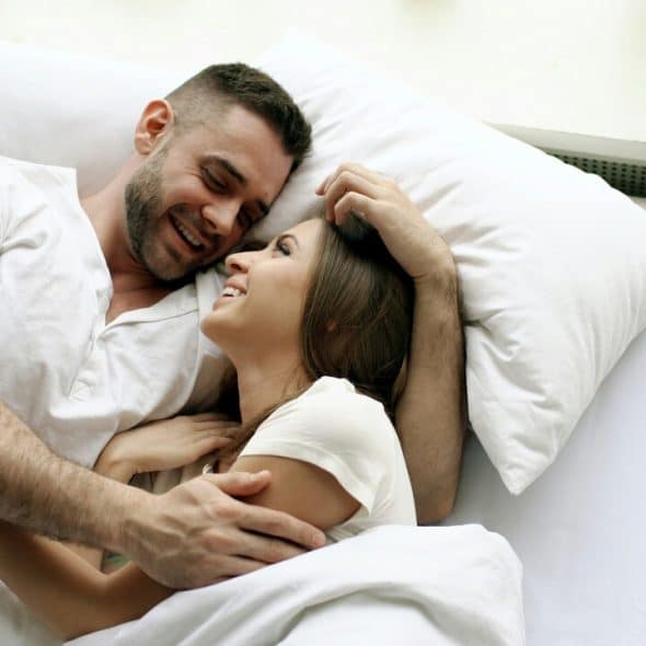 A couple smiling at each other in bed
