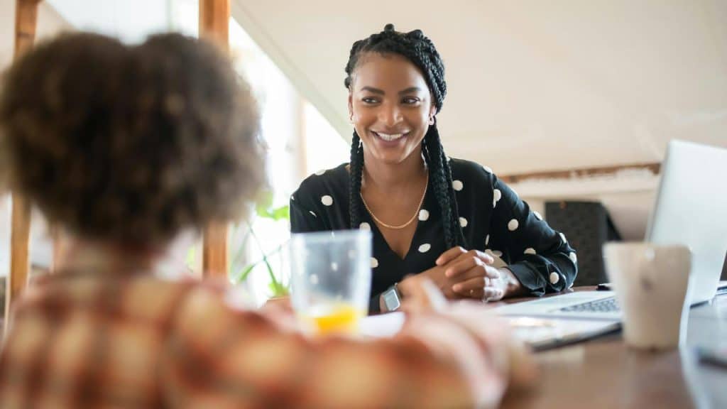 A woman smiling while talking to someone across a table.