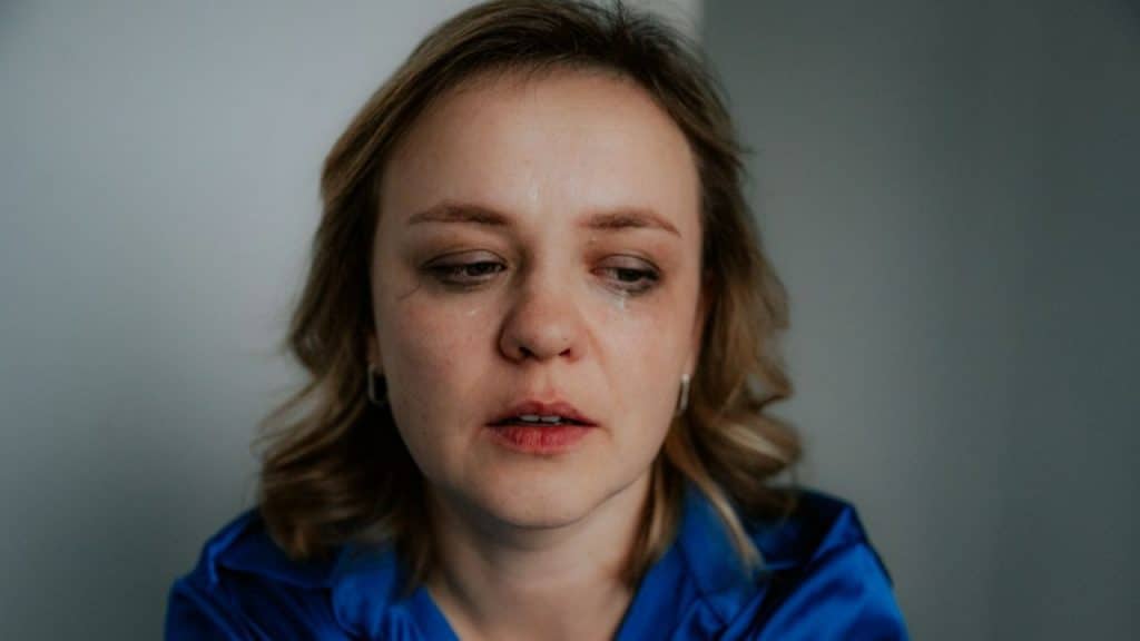 Close-up of a blonde woman crying with visible mascara streaks on her cheeks.
