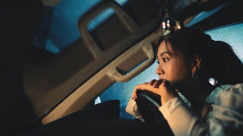 Woman with a pensive expression sitting in a car at night.