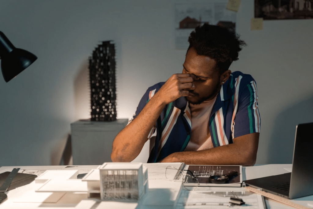 Man Sitting In Front of His Work Table Feeling Exhausted
