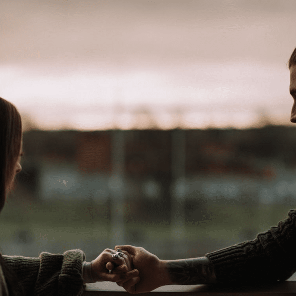 Cropped couple holding hands on balcony at sunset