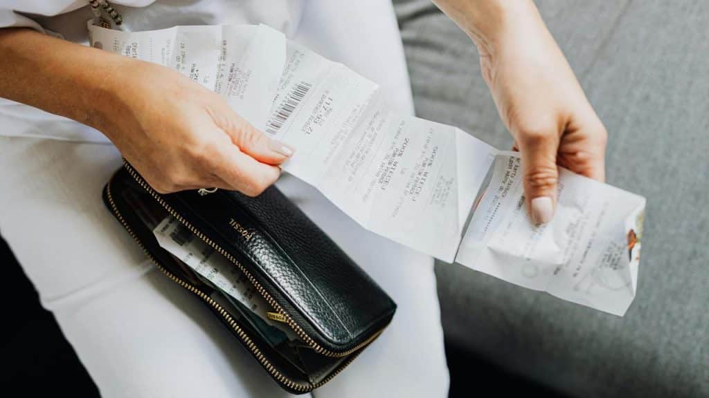 A person holding several receipts and a black wallet.