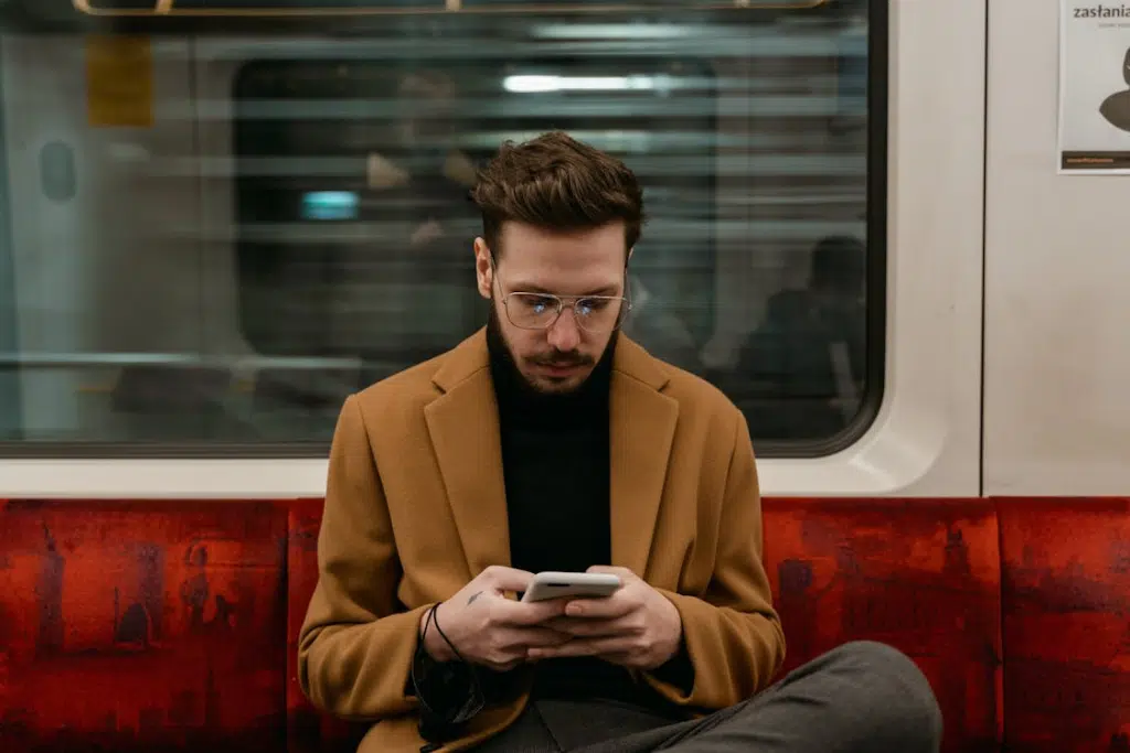 A Man in Brown Coat Using a Smartphone in a Train
