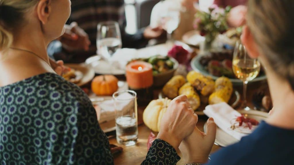 A group of people praying at a dinner table before eating.