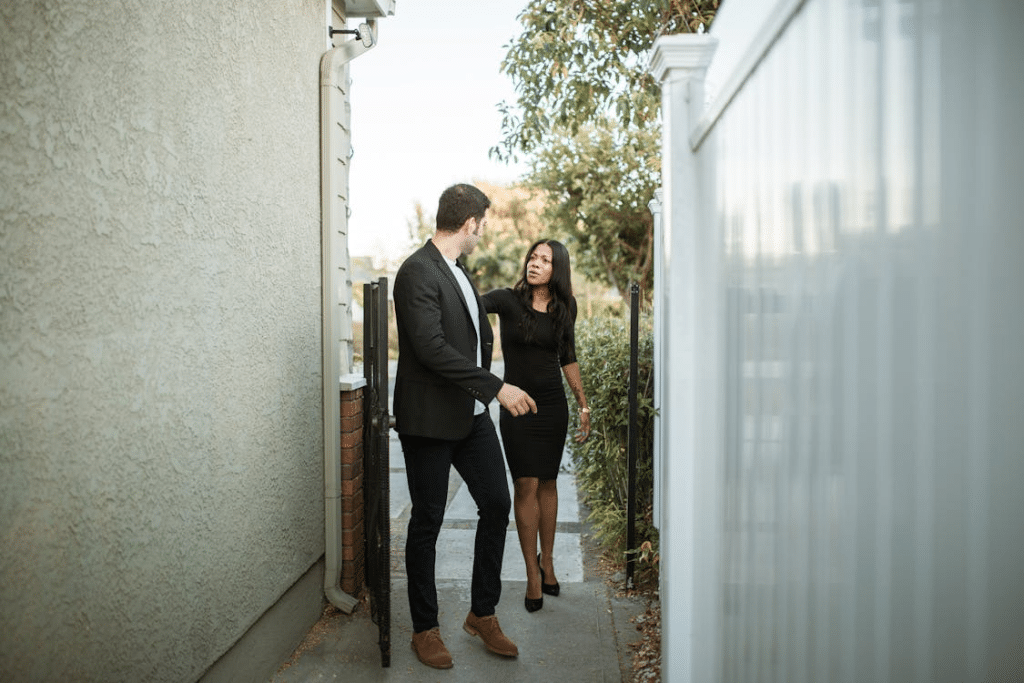 A man in a black suit walking with a woman in a black dress